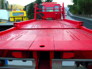 looking at the back of a freshly painted red flatbed tow truck