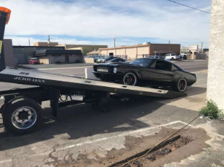 flatbed tow truck pulling a dodge charger on the back